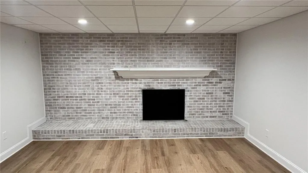 Detailed view of a paneled ceiling, wood finished floors, recessed lighting, and a fireplace