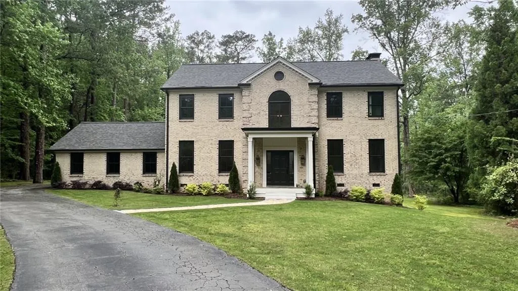View of front of property with brick siding, a front yard, and a chimney