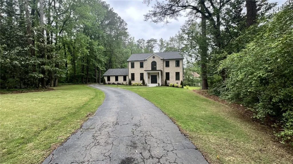 Colonial inspired home with a front yard, stone siding, asphalt driveway, and brick siding