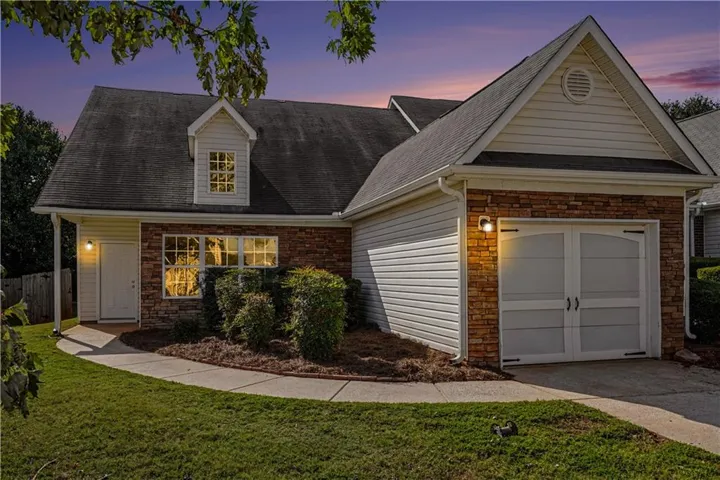 Exterior featuring stone and siding finishes, a prominent dormer window, and an attached garage with arched doors