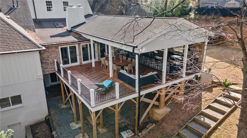 Back of property with roof with shingles, a patio, and a wooden deck