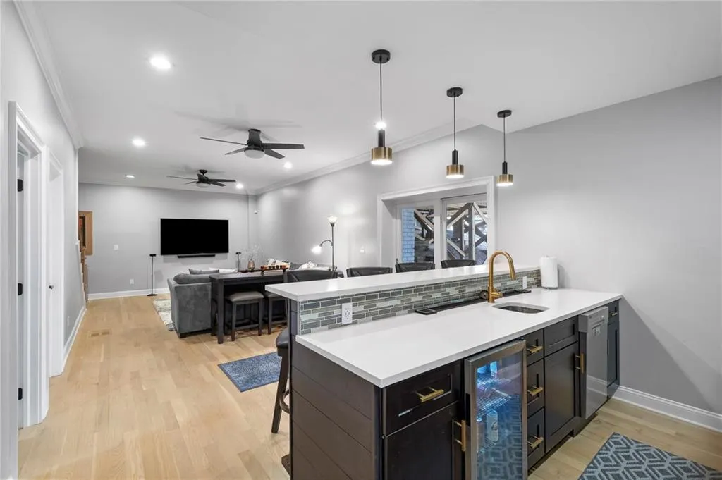 Kitchen featuring a kitchen breakfast bar, a peninsula, wine cooler, a ceiling fan, and open floor plan