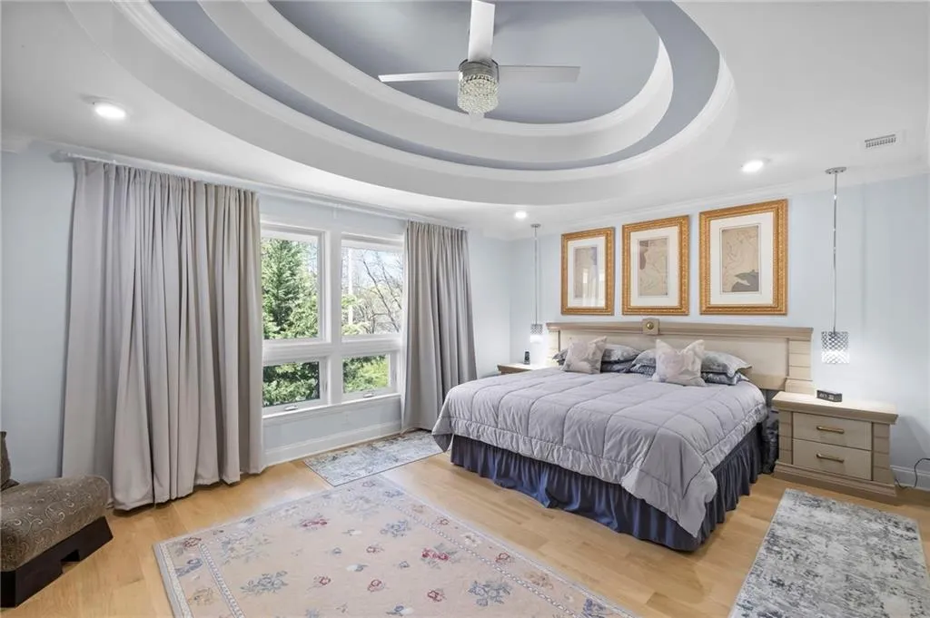 Bedroom featuring light wood-type flooring, a ceiling fan, recessed lighting, a raised ceiling, and ornamental molding