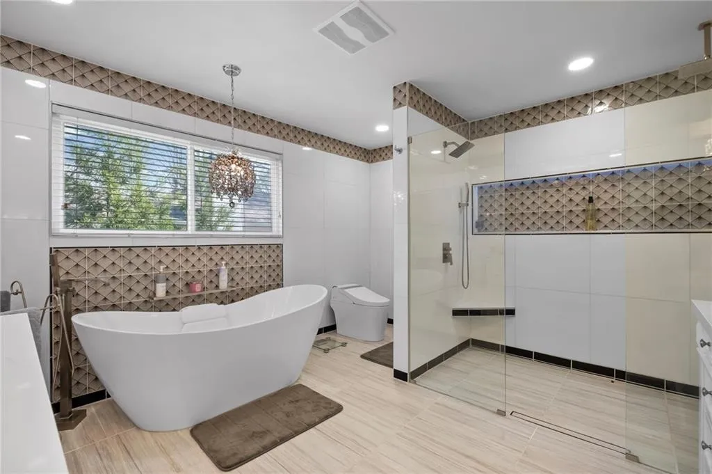 Full bath featuring tile walls, a walk in shower, a freestanding bath, and vanity