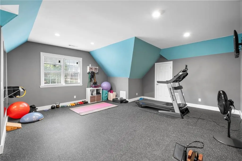 Exercise room with vaulted ceiling and recessed lighting