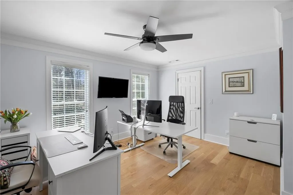 Home office with ornamental molding, light wood-style flooring, and ceiling fan