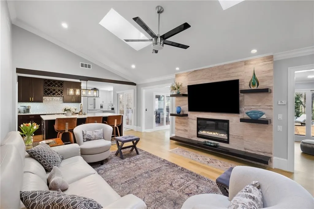 Living area featuring crown molding, lofted ceiling, light wood-type flooring, a tile fireplace, and healthy amount of natural light