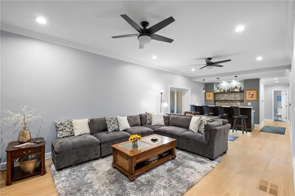 Living area featuring ornamental molding, light wood finished floors, recessed lighting, bar, and a ceiling fan