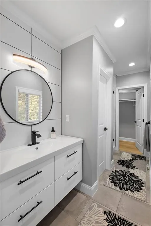 Bathroom featuring ornamental molding, vanity, recessed lighting, and a walk in closet