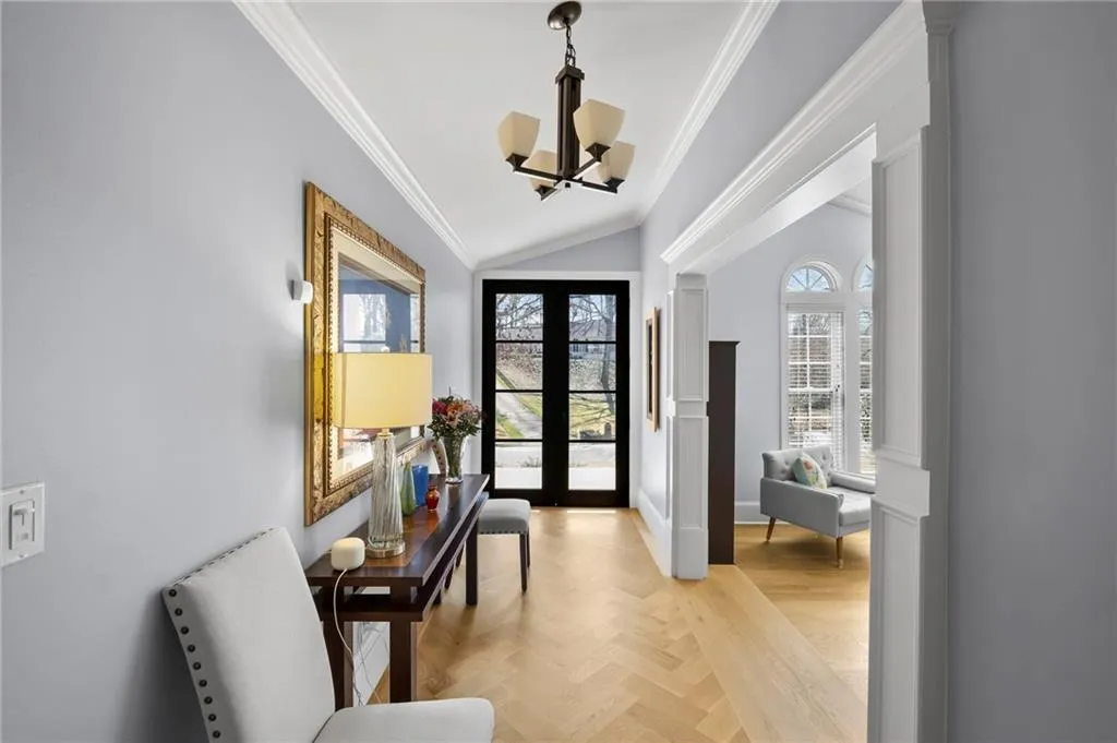 Entrance foyer featuring vaulted ceiling, parquet flooring, a chandelier, french doors, and crown molding