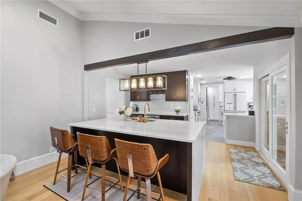 Kitchen featuring a breakfast bar, dark wood finish cabinets, built in fridge, vaulted ceiling, and decorative light fixtures