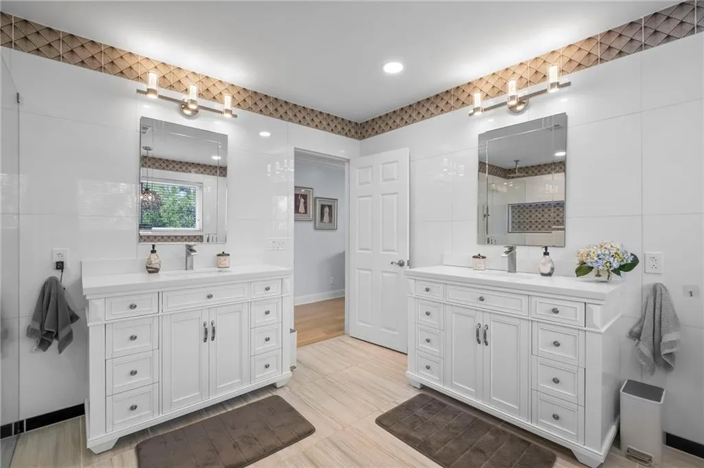 Bathroom featuring tile walls, two vanities, and a tile shower