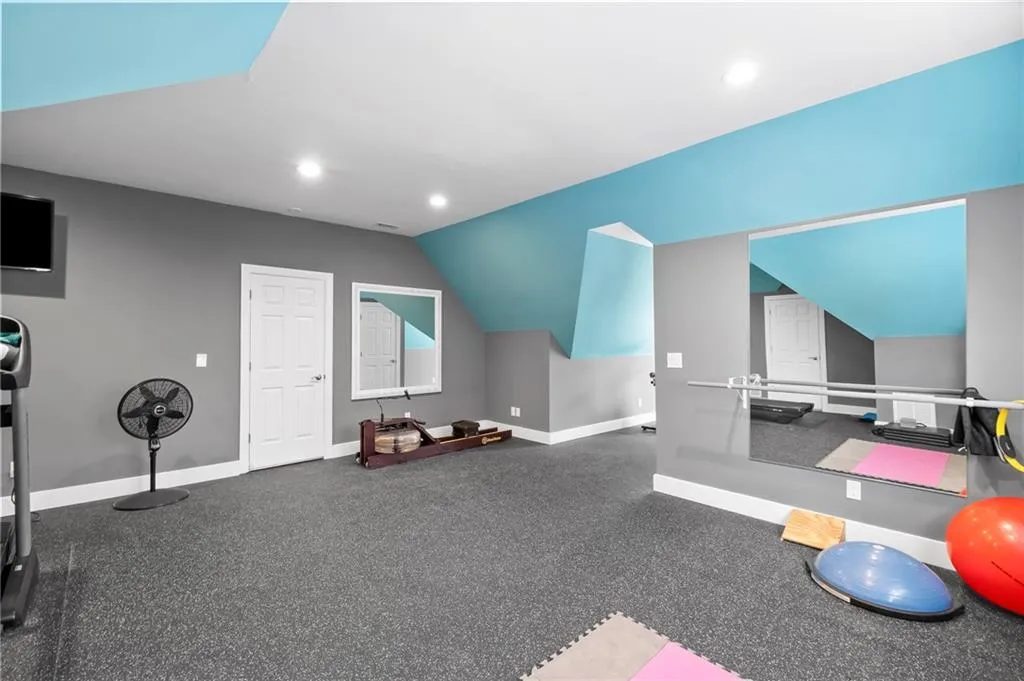 Workout room featuring vaulted ceiling and carpet floors