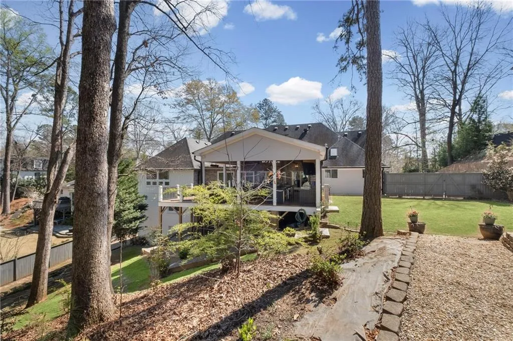 Rear view of house featuring a fenced backyard, roof with shingles, and a sunroom