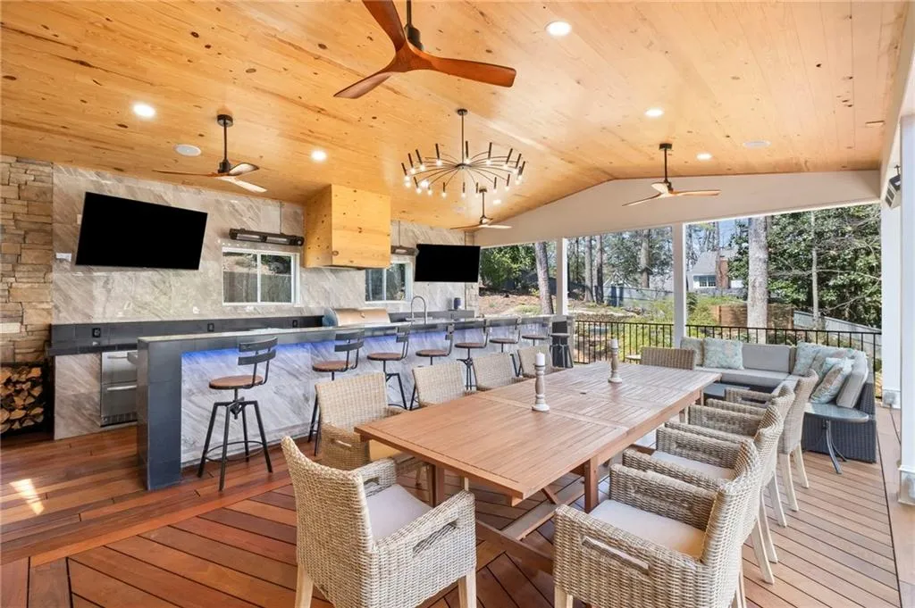 Wooden terrace featuring a ceiling fan, area for grilling, and an outdoor bar and dining area