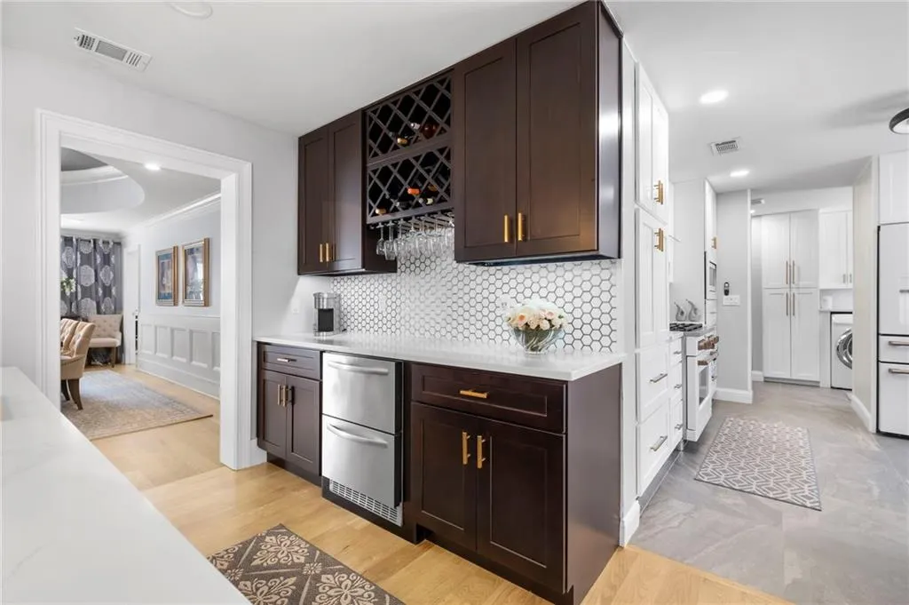 Indoor dry bar featuring dark wood finish cabinets, recessed lighting, high quality appliances, washer / dryer, and light wood-style floors