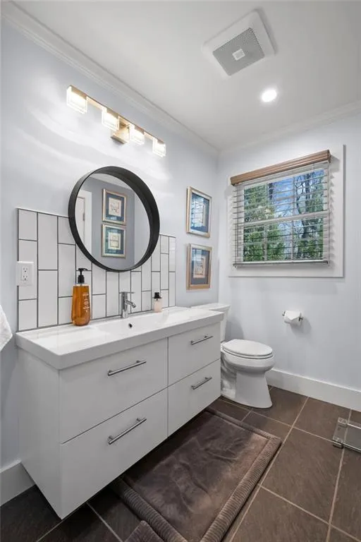 Bathroom featuring crown molding, vanity, dark tile patterned flooring, backsplash, and recessed lighting