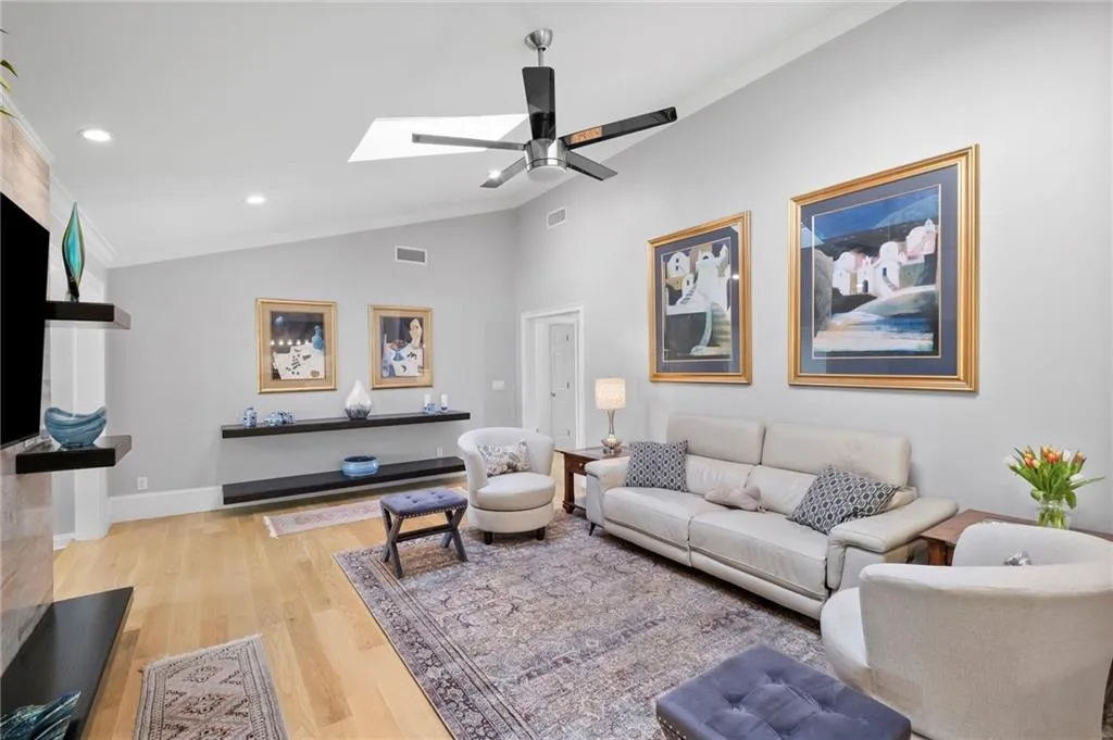 Living area featuring light wood-style flooring, vaulted ceiling, recessed lighting, ornamental molding, and ceiling fan