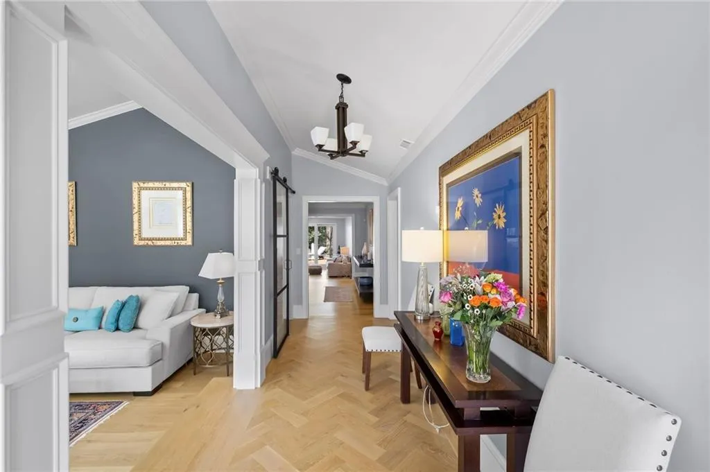 Hallway with a barn door, crown molding, parquet flooring, lofted ceiling, and a chandelier