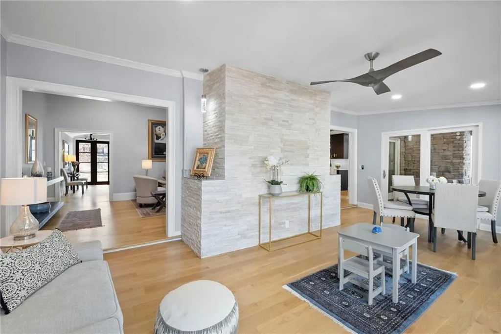 Living area with light wood-style flooring, ceiling fan, and crown molding