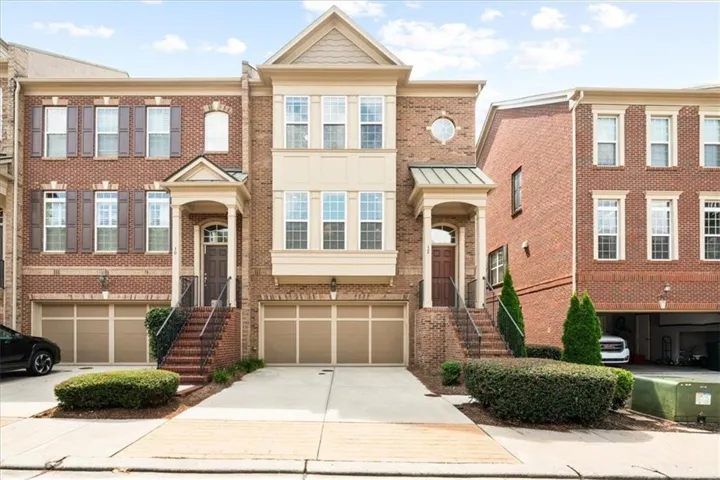 Brick exterior with decorative shutters, integrated two-car garage, covered entry, and manicured shrubbery
