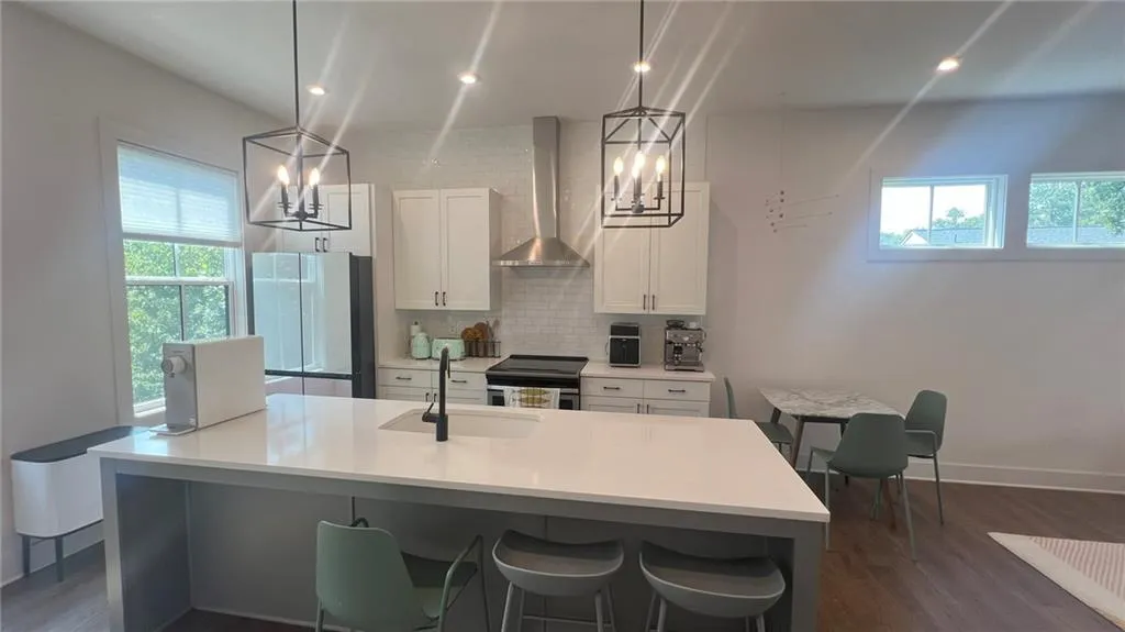 Kitchen with dark wood-style flooring, backsplash, wall chimney exhaust hood, freestanding refrigerator, and recessed lighting