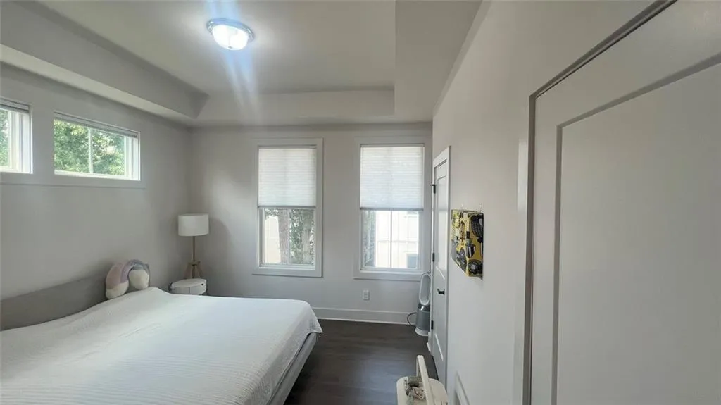 Bedroom featuring dark wood-style flooring and a tray ceiling