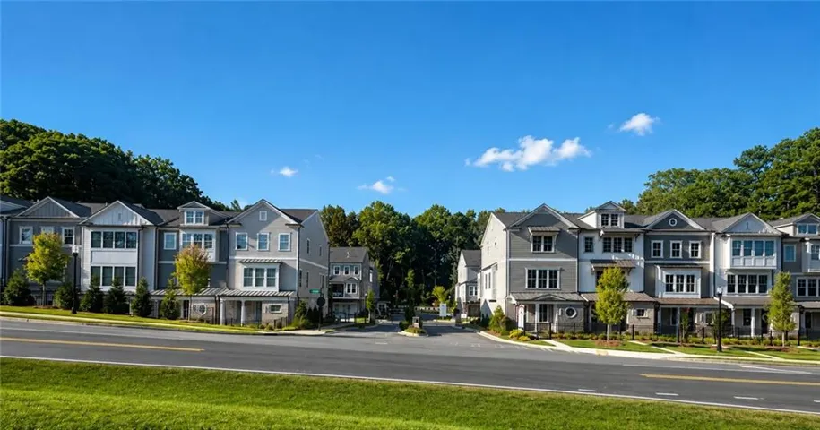 Modern townhome community featuring varied architectural styles, a paved street, and mature landscaping