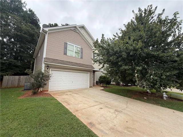 Two-story residence with siding exterior, attached two-car garage, concrete driveway, and established landscaping