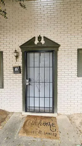 Charming brick exterior featuring a dark-framed entry door with decorative grid detailing and pediment crown molding