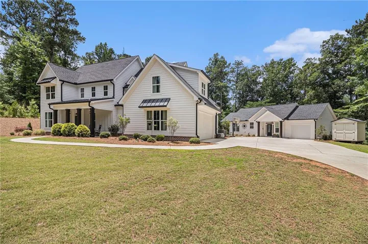 Modern Farmhouse estate featuring a two-story cream exterior with black-trimmed windows, brick chimney detailing, and a covered front portico