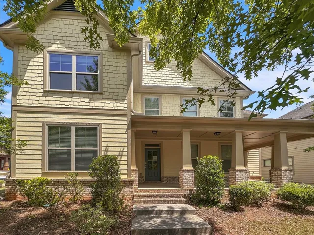 Shingle and clapboard siding exterior with brick accents, covered front porch, and mature landscaping