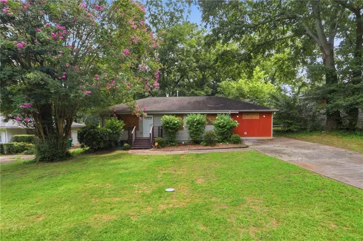 Ranch-style residence featuring a prominent red facade accent and a concrete driveway
