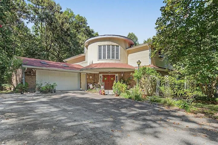Circular architectural element, multi-pane windows, and a two-car garage with a red-shingled roof
