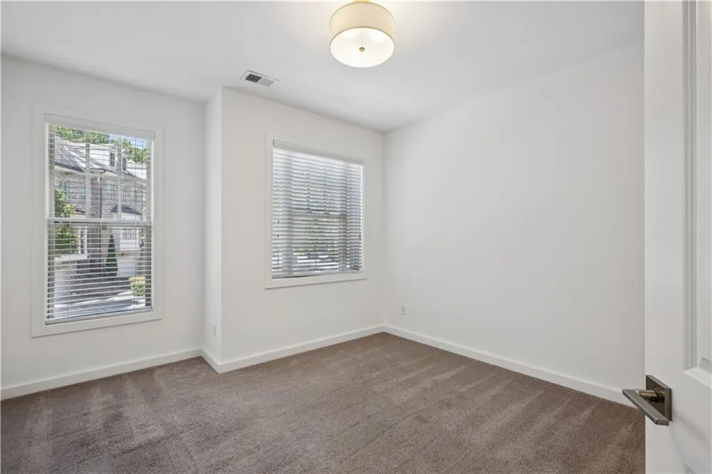 Unfurnished room with healthy amount of natural light and dark carpet