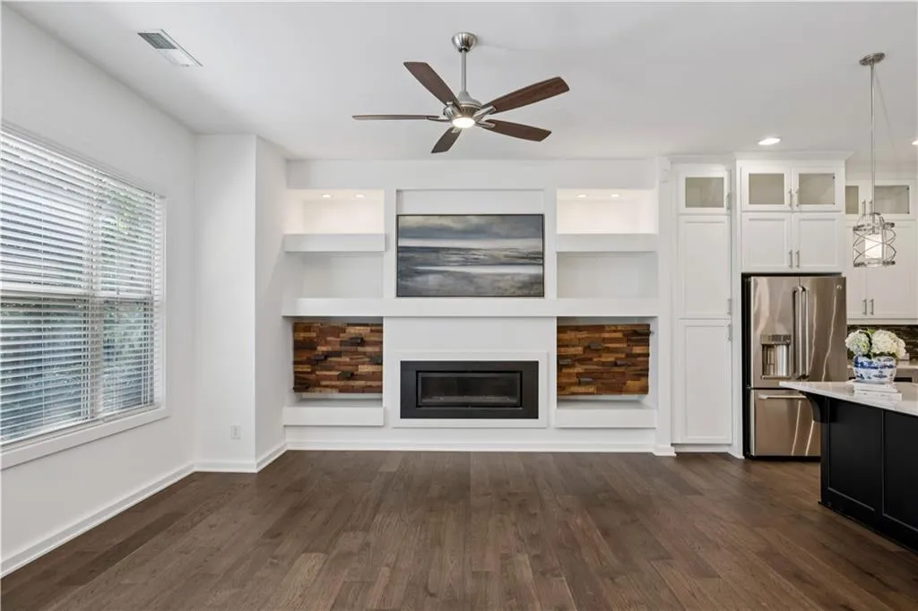 Unfurnished living room featuring dark wood-style floors, a glass covered fireplace, ceiling fan, and recessed lighting