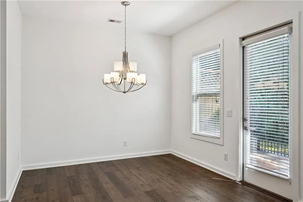 Unfurnished dining area featuring dark wood-style floors and a chandelier