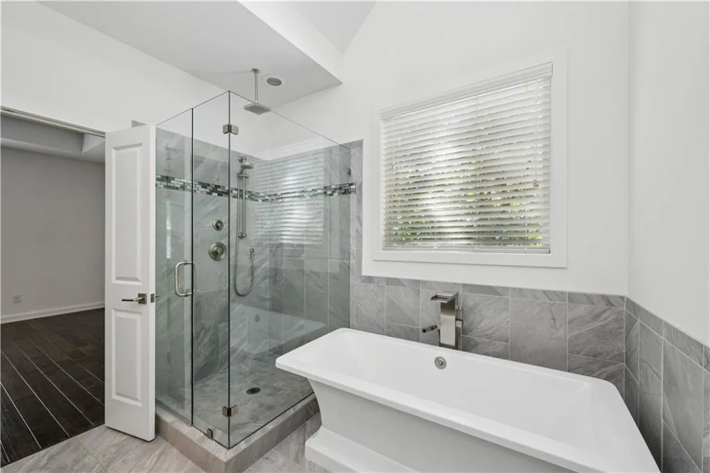 Full bath with a freestanding tub, a shower stall, and tile walls