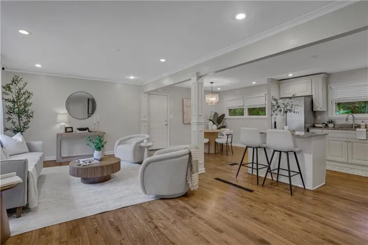 Open-concept living space featuring wood-finish flooring, recessed lighting, and crown molding