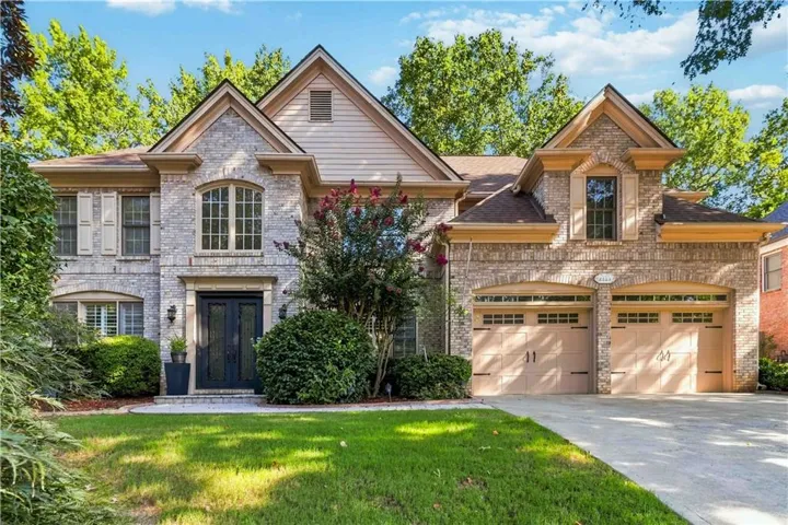 Brick and stone facade residence featuring a double-door entry, arched windows, and a two-car garage with carriage-style doors