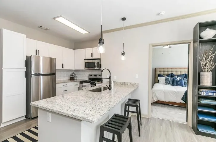 Kitchen with pendant lighting, stainless steel appliances, a kitchen bar, light wood-style flooring, and white cabinetry