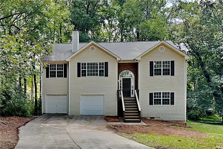 Split-level residence featuring a brick archway entrance, dual garage doors, and a concrete driveway