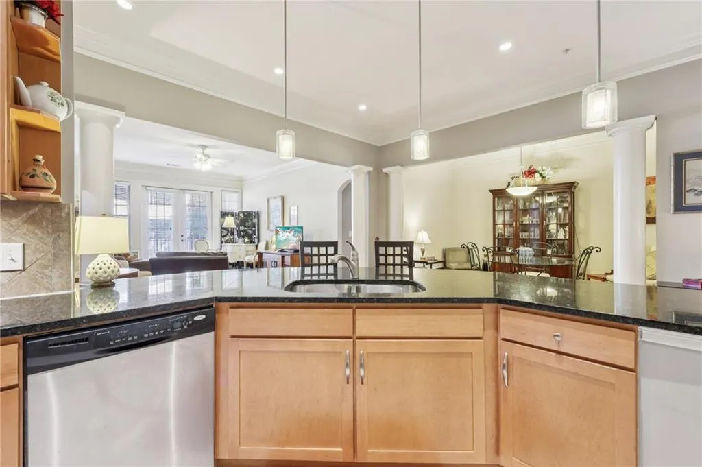 Kitchen with ornate columns, stainless steel dishwasher, open floor plan, ornamental molding, and light brown cabinets Kitchen with ornate columns, stainless steel dishwasher, open floor plan, ornamental molding, and light brown cabinets