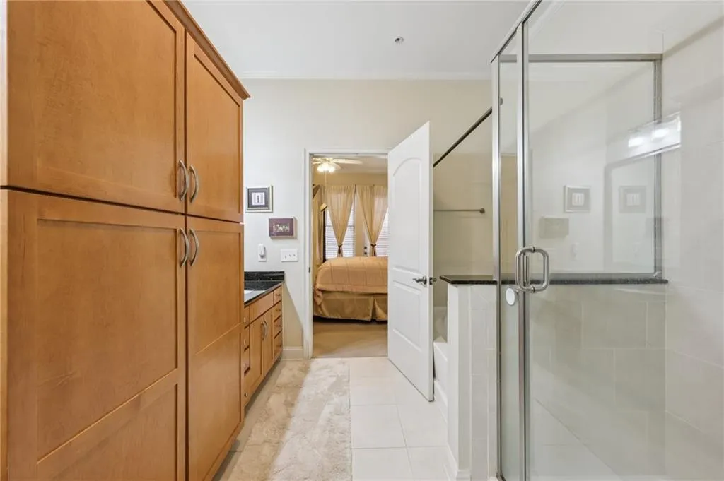 Full bath featuring ensuite bath, a shower stall, light tile patterned floors, ceiling fan, and vanity Full bath featuring ensuite bath, a shower stall, light tile patterned floors, ceiling fan, and vanity