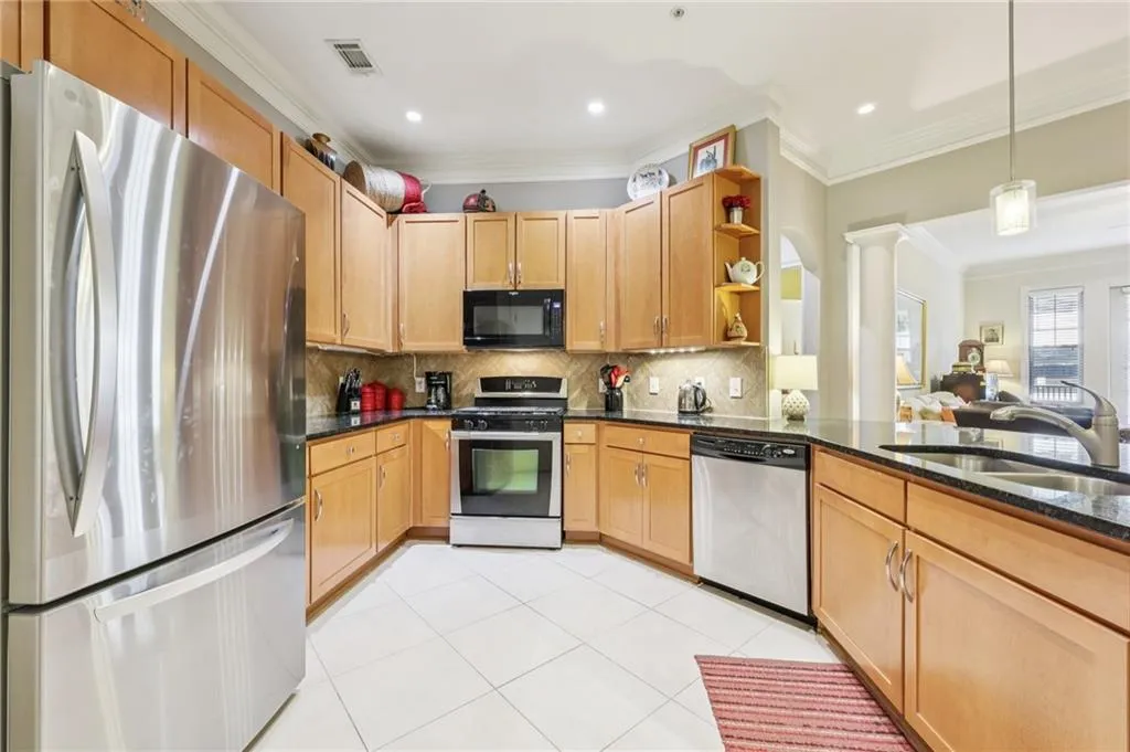 Kitchen with appliances with stainless steel finishes, crown molding, tasteful backsplash, dark stone counters, and open shelves Kitchen with appliances with stainless steel finishes, crown molding, tasteful backsplash, dark stone counters, and open shelves