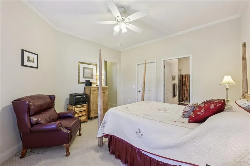 Carpeted bedroom with ornamental molding, ceiling fan, and ensuite bathroom Carpeted bedroom with ornamental molding, ceiling fan, and ensuite bathroom