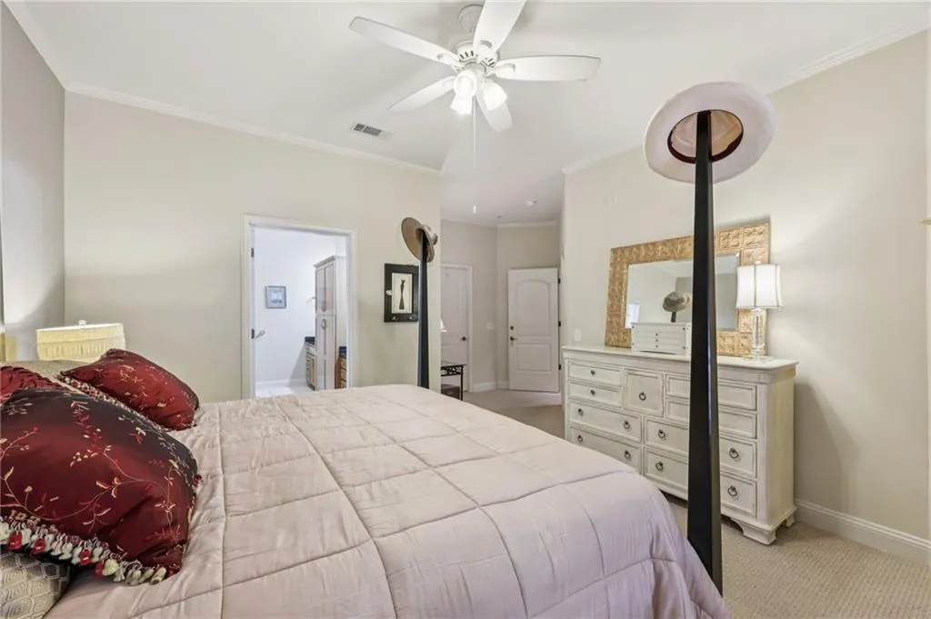 Bedroom with light carpet, ornamental molding, a ceiling fan, and ensuite bathroom Bedroom with light carpet, ornamental molding, a ceiling fan, and ensuite bathroom