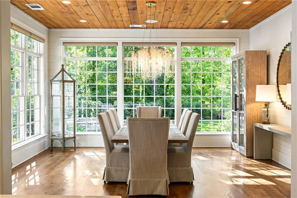 Sun-lit dining room with serene views of Mother Nature's tree-lined backdrop