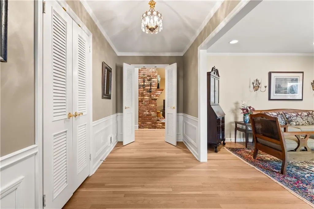 Hall featuring a chandelier, light wood-style floors, crown molding, recessed lighting, and a wainscoted wall
