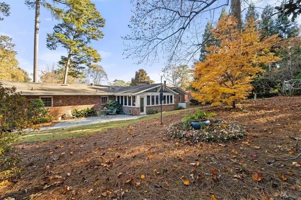 Back of property with a patio area, a sunroom, and brick siding
